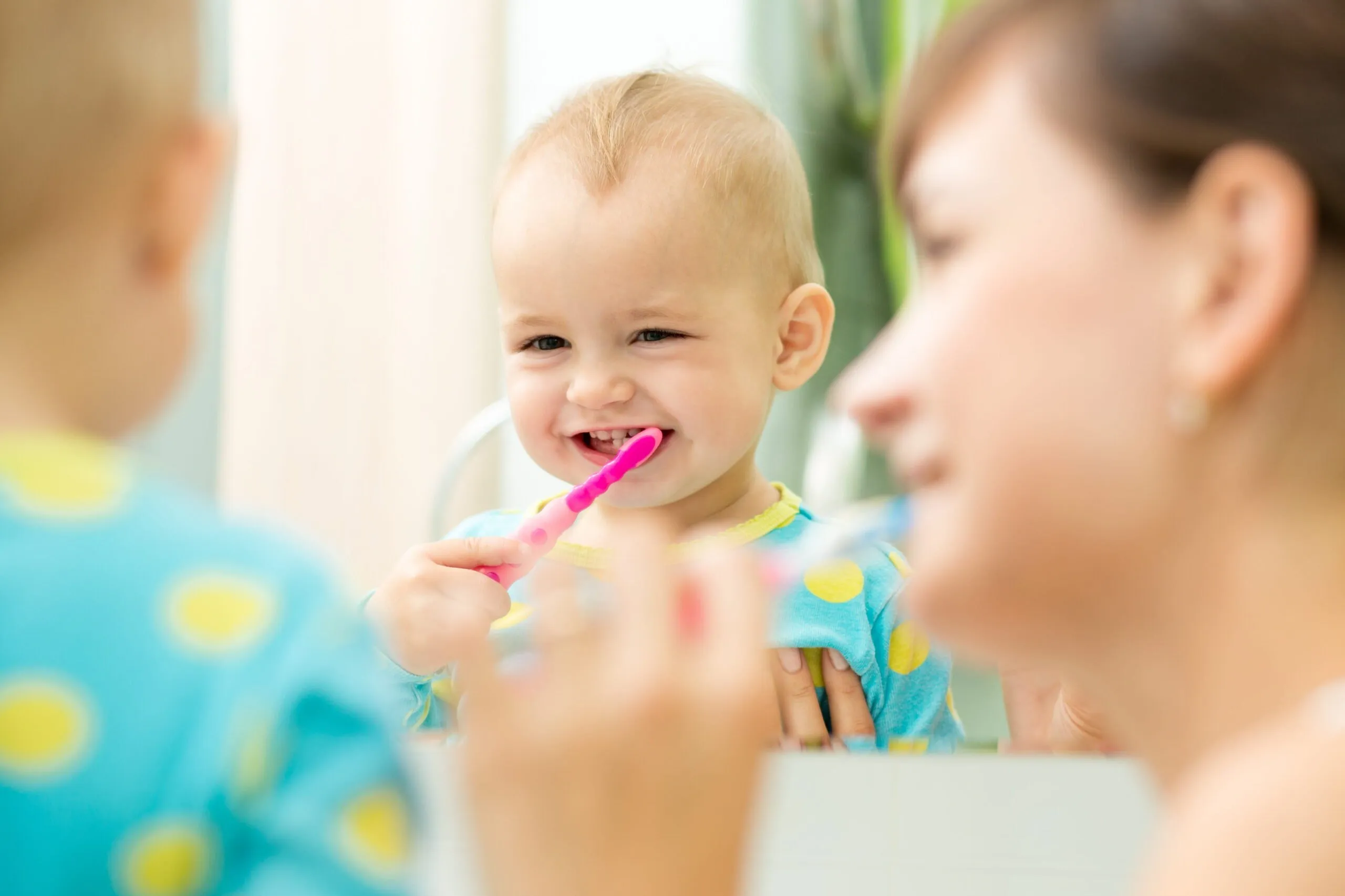 AdobeStock_74434918 mother and kid look at mirror during teeth brushing