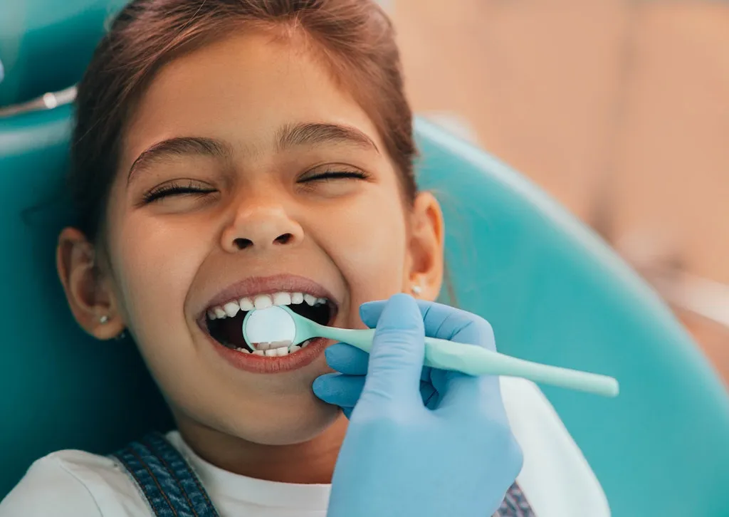 Cute little girl getting teeth exam at dental clinic