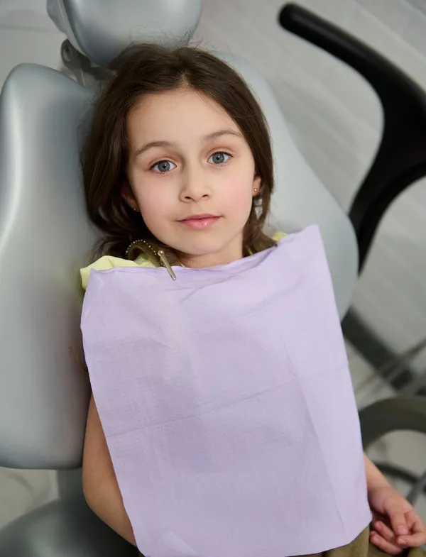 Portrait of a beautiful happy kid girl patient at dentist appointment for teeth cleaning, oral checkup or consultation. Beautiful happy kid girl patient at dentist appointment for teeth cleaning, dental checkup and consultation. Pediatric dentistry. Oral care and hygiene. Diagnosis and prevention of baby teeth caries