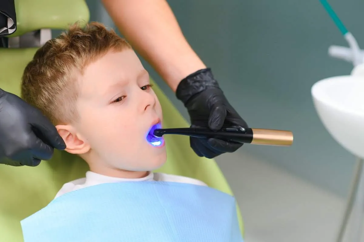Scared red-haired boy crying at reception at dentist in dental chair. Pediatric dentistry.