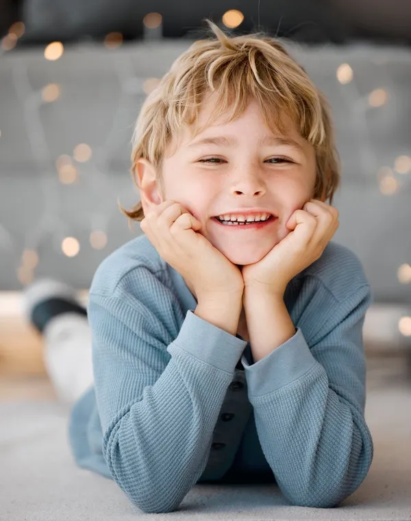 Portrait smile, boy and lying on floor in home for wellness, relax and alone time with bokeh lights. Face, young child and happy on carpet with healthy gums, clean mouth and dental care for teeth Portrait smile, boy and lying on floor in home for wellness, relax and alone time with bokeh lights. Face, young child and happy on carpet with healthy gums, clean mouth and dental care for teeth.