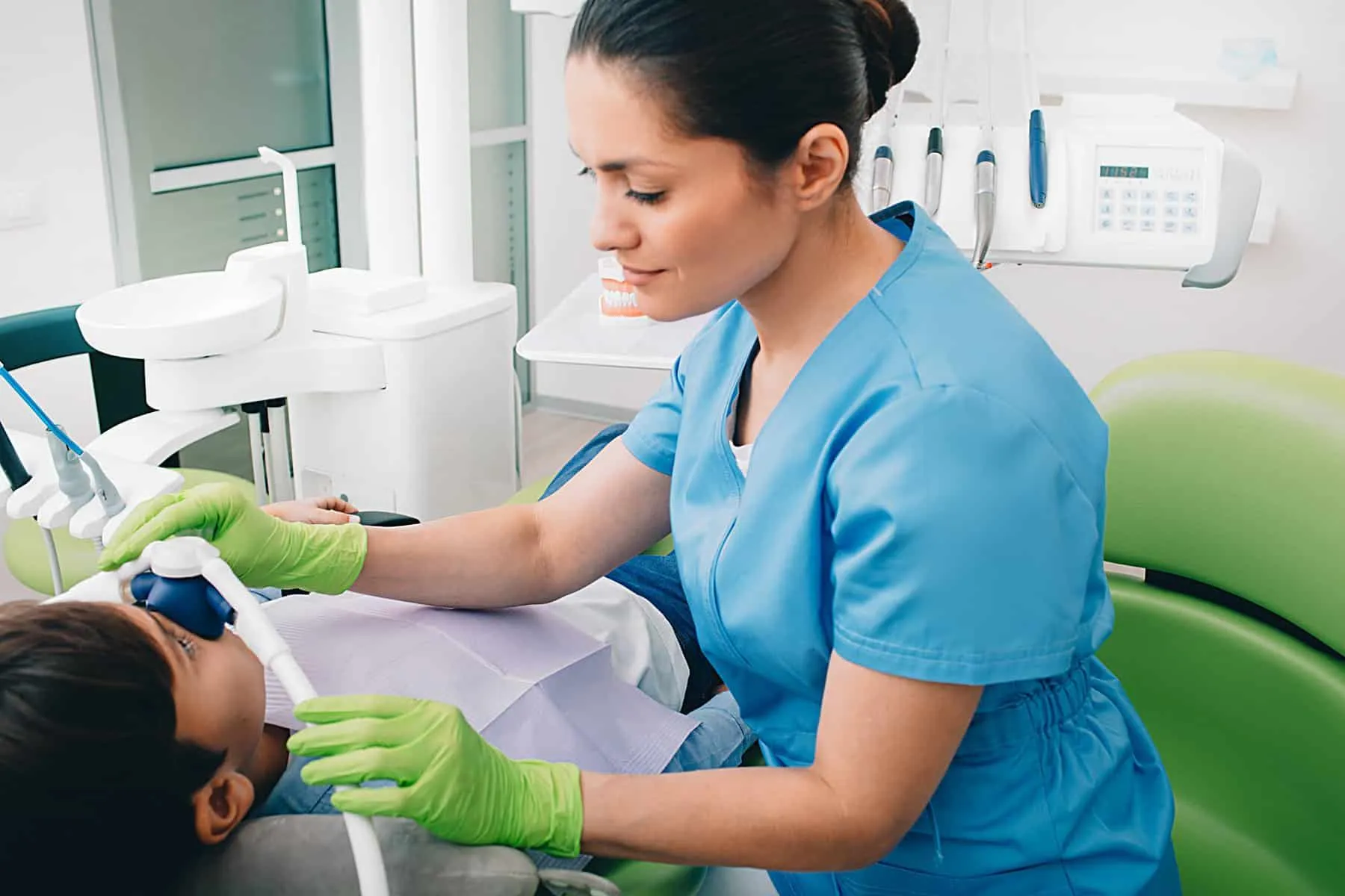 Pediatric dentist doing Inhalation Sedation to a child while teeth treatment at dental clinic. Sedation Dentistry Pediatric dentist doing Inhalation Sedation to a child while teeth treatment at dental clinic. Sedation Dentistry