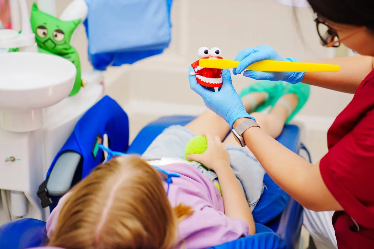 Cheerful pediatric dentist with a patient. training in proper brushing Cheerful pediatric dentist with a patient. training in proper brushing