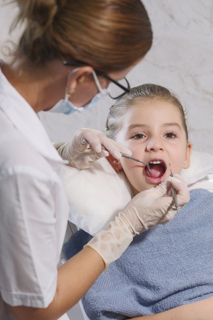 5 year old girl in pediatric dentistry office, the dentist is assisting her.