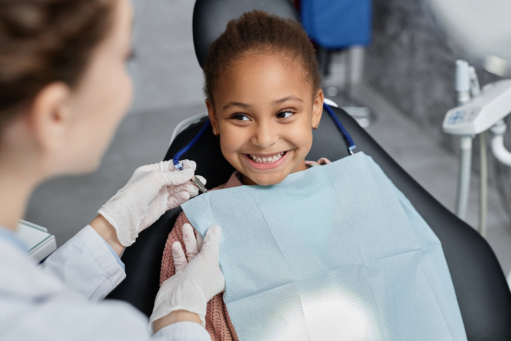 Smiling little girl in dental chair with nurse preparing her for teeth check up Portrait of smiling little girl in dental chair with nurse preparing her for teeth check up, copy space