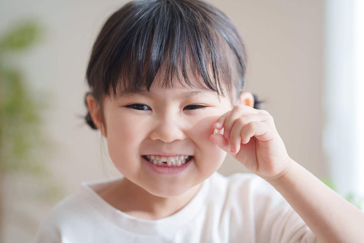 乳歯が抜けた子供 Child holding her tooth