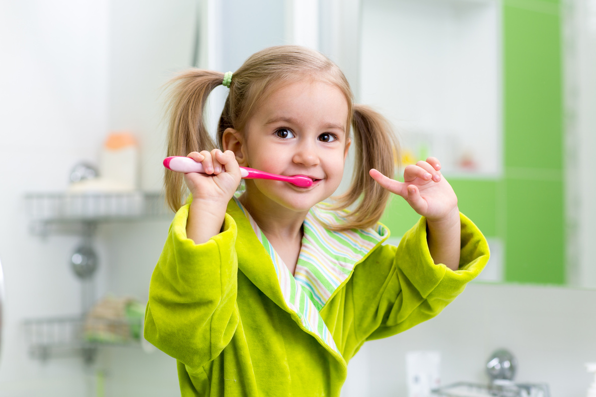 kid girl brushing teeth in bathroom