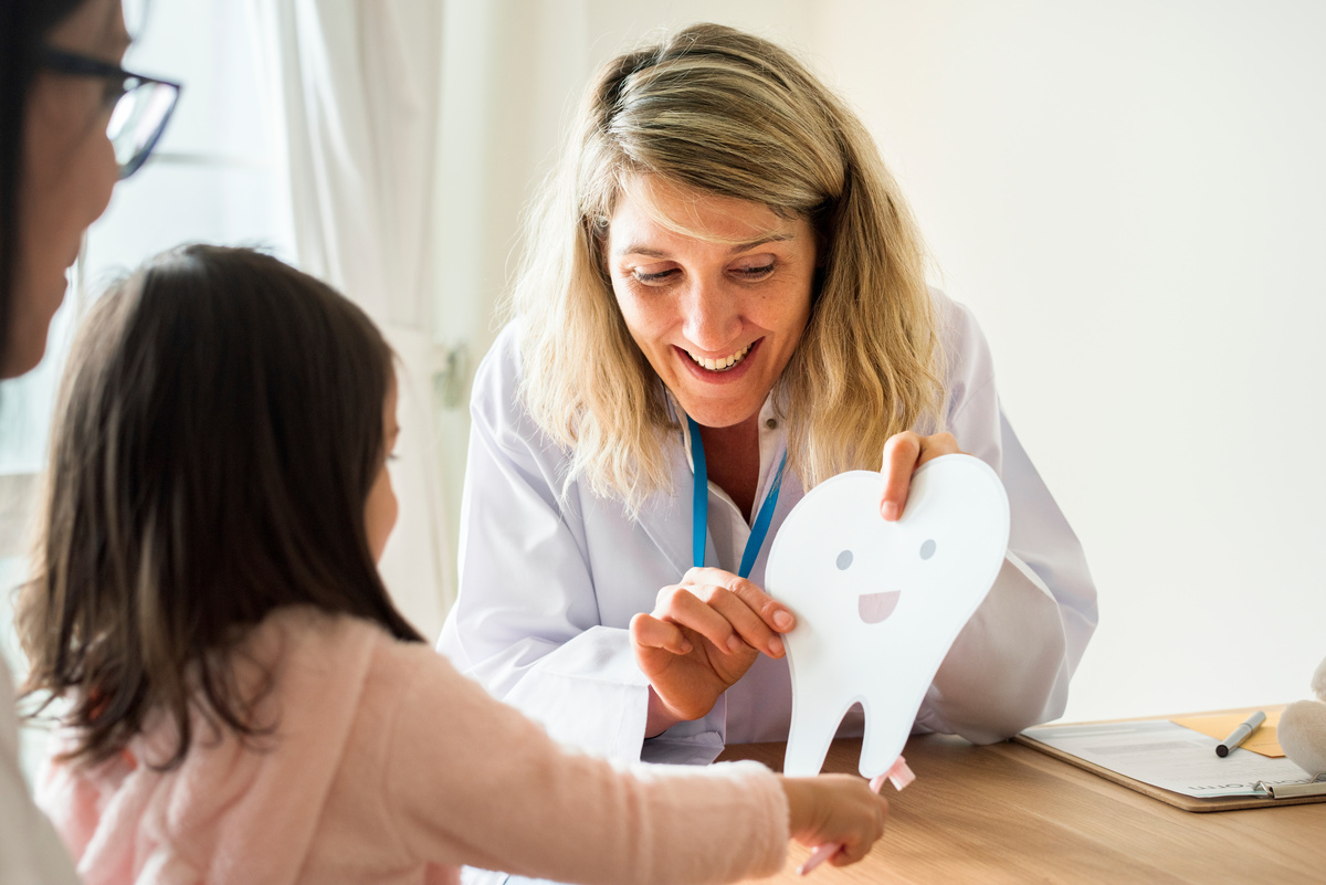 Dentist teaching little girl how to brush teeth Dentist teaching little girl how to brush teeth