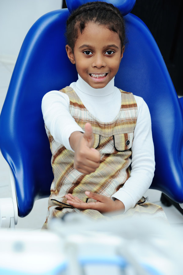 little African girl with dark skin in dentistry baby girl with dark skin in blue dental chair