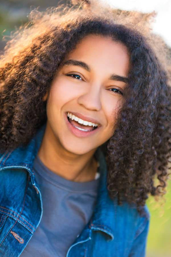 Outdoor portrait of beautiful happy mixed race African American girl teenager female young woman smiling laughing with perfect teeth Outdoor portrait of beautiful happy mixed race African American girl teenager female young woman smiling laughing with perfect teeth