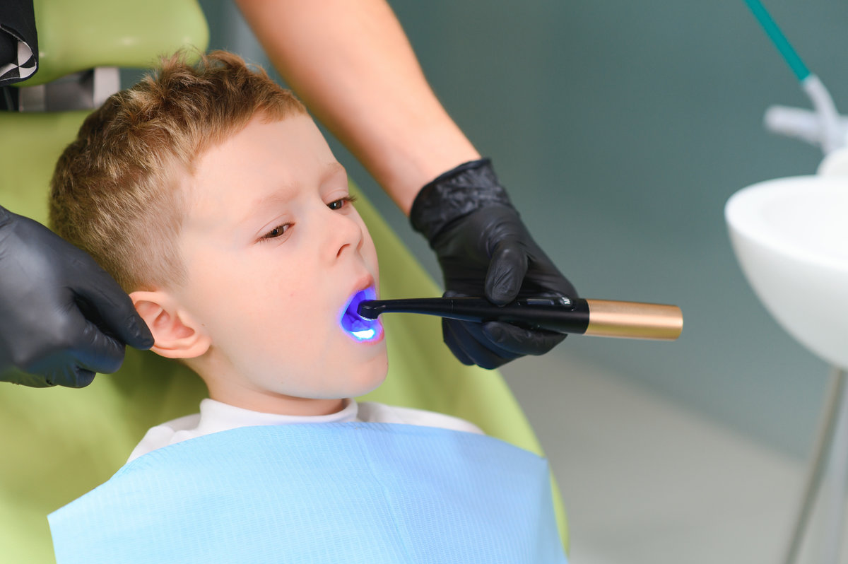 Scared red-haired boy crying at reception at dentist in dental chair. Pediatric dentistry.