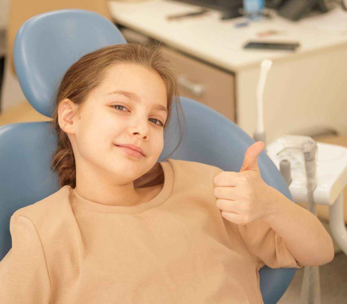 The hands of an unrecognizable pediatric dentist conducting an examination procedure for a smiling cute little girl sitting on an armchair in the office. A little girl sitting at the dentist. The hands of an unrecognizable pediatric dentist conducting an examination procedure for a smiling cute little girl sitting on an armchair in the office. Dentist's office. A little girl sitting at the dentist.