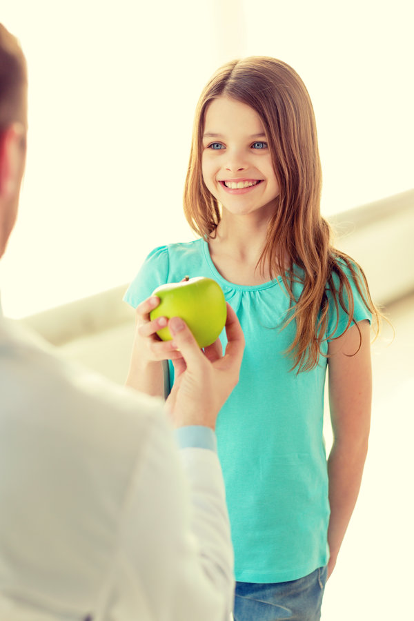 male doctor giving an apple to smiling little girl healthcare, child and medicine concept - male doctor giving an apple to smiling little girlhealthcare, child and medicine concept - male doctor giving an apple to smiling little girl