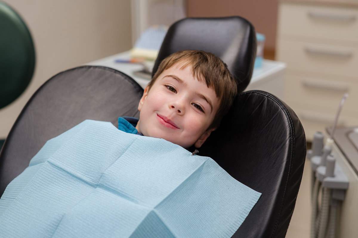 A cute little boy in a dental chair treats his teeth, smiling and happyA cute little boy in a dental chair treats his teeth, smiling and happy