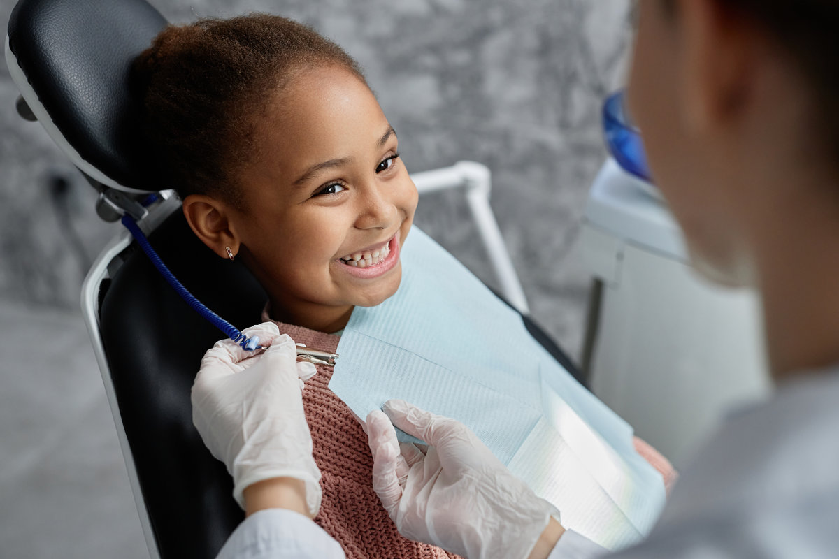 Cute black girl in dental chair with nurse or dentist Portrait of cute black girl in dental chair with nurse or dentist preparing her for teeth exam, copy space