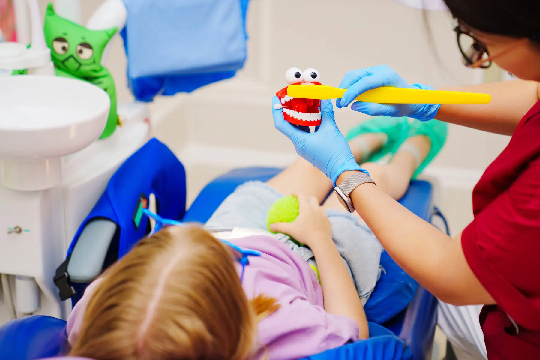 Cheerful pediatric dentist with a patient in a dental chair. training in proper brushing and oral hygiene. modern painless dental treatment.
